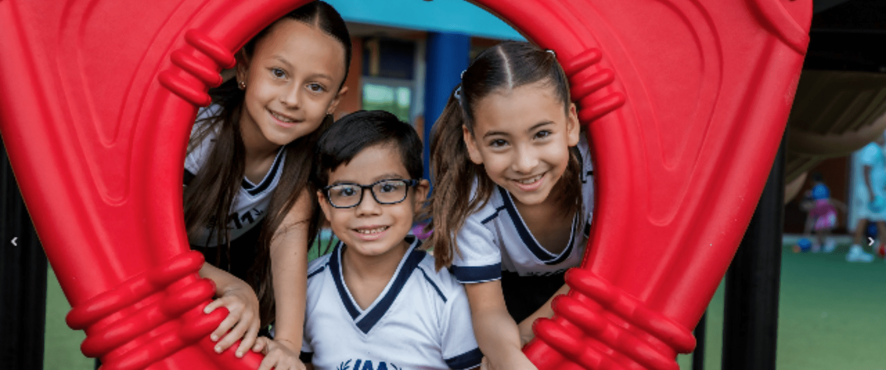 Tres alumnos de Primaria del Instituto Anglo Moderno sonriendo en los juegos del patio